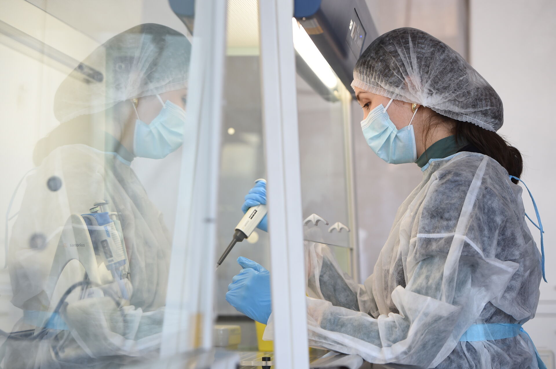 Portrait of researcher in personal protective equipment holding a pipette in a biocontainment hood